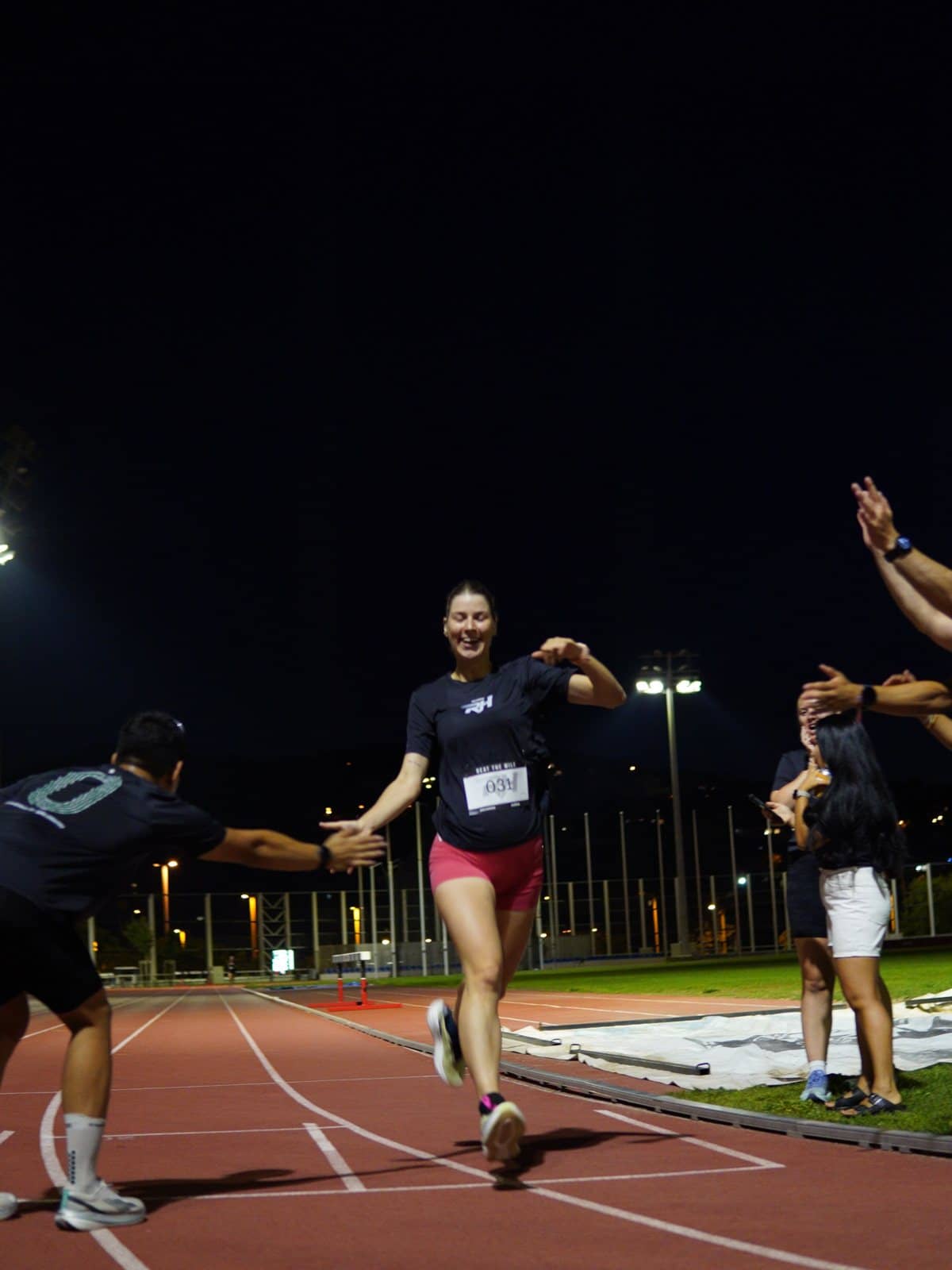 A runner high-fives the crowd on the track at Beat The Mile
